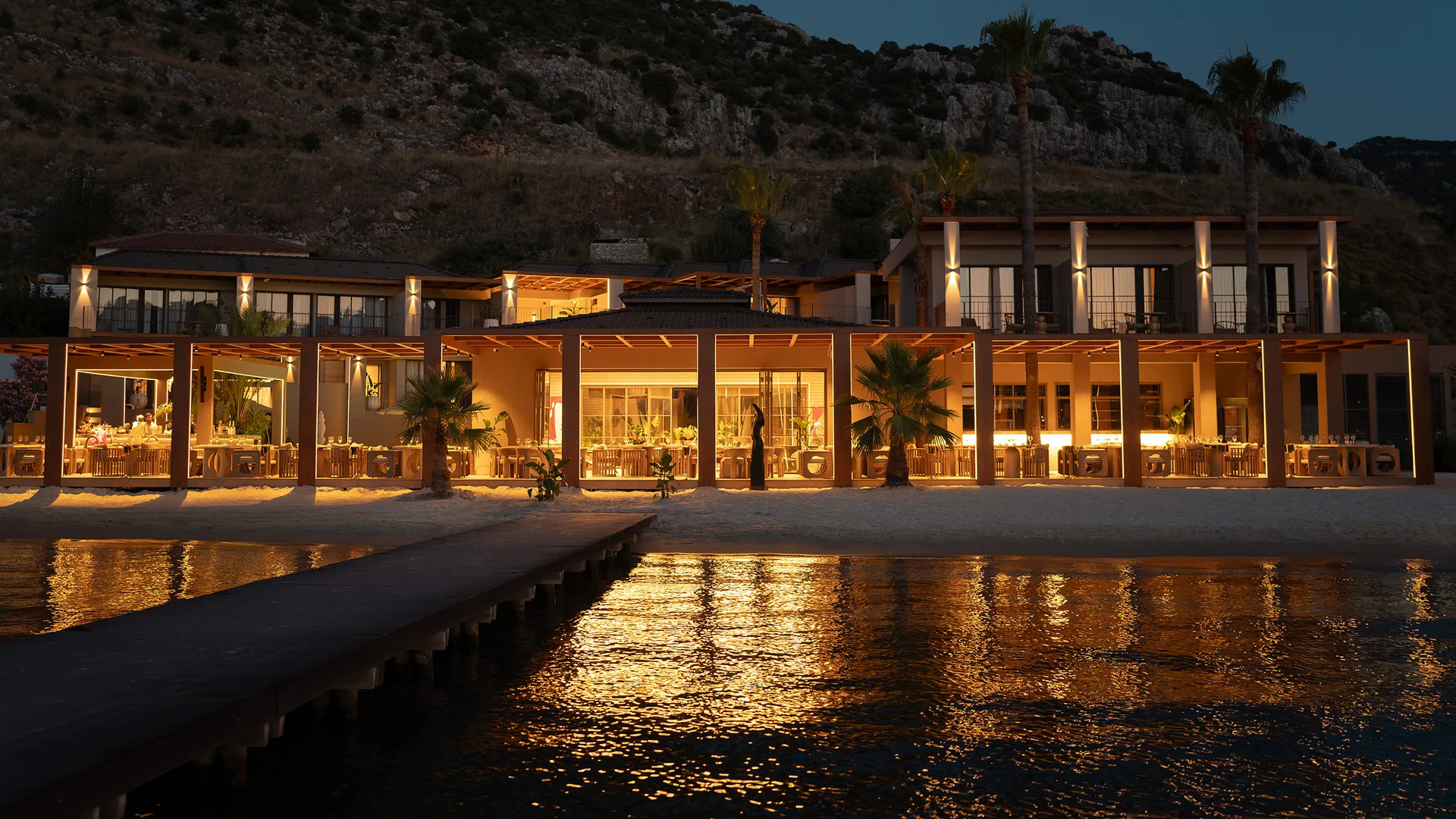 Oumu Beach House - After sunset, dock, sea and the hotel in lights.